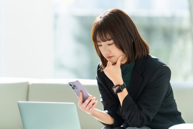 隙間時間にできる仕事をスマホで探し、考え込む女性のイメージ