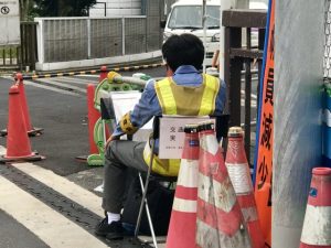 交差点脇でカウンターを使い交通量を記録する調査員