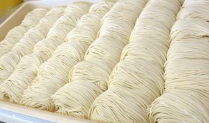 食品工場でトレーに整列する麺の製造工程