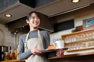 カフェでトレーを持って配膳する女性スタッフ