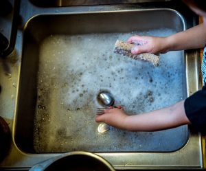 飲食店の閉店作業でシンクに泡を立てて食器を洗っている手元