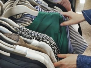 リサイクルショップで洋服のハンガーを掛け替える作業風景