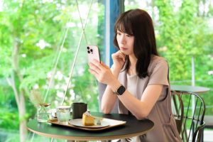 カフェでスマホを見ながら仕事を探す女性のイメージ