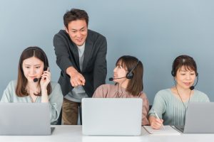 社員のサポートを受けながら電話対応を行うコールセンタースタッフ