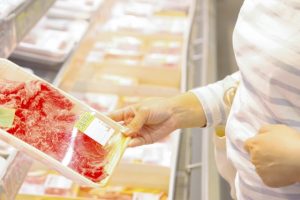 スーパーのお肉売り場でパック商品を手に取る様子