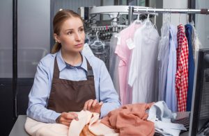 クリーニング店の受付でスタッフが衣類の状態を確認している様子