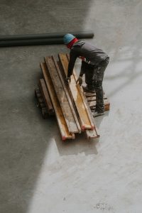 建設現場で木材資材を整理する作業員。荷揚げ屋バイトで重量資材を扱う様子をイメージした写真