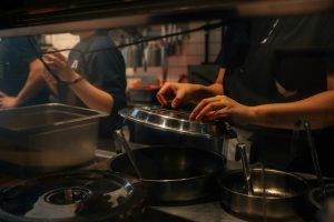 居酒屋の厨房で鍋や調理器具を扱いながら調理補助をするスタッフの手元