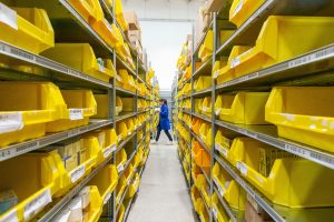 番号が付いた棚が並ぶ室内倉庫で商品を仕分ける作業風景