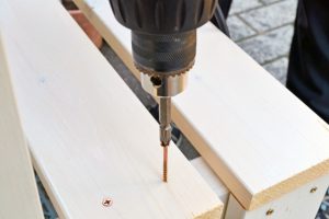 木材に電動ドリルでネジを締めている組み立て作業の手元
