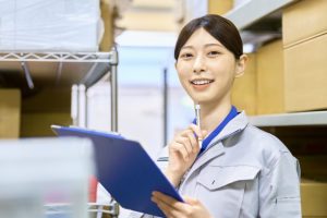 倉庫内でクリップボードを見ながら作業内容を確認するスタッフ