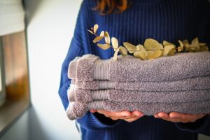 畳まれたタオルを手に持つ人物とサロンの洗濯物整理をイメージした写真